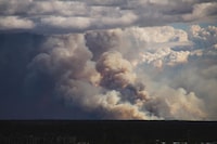 This August 13, 2023 image provided by Sylvia Webster shows smoke rising from wildfires near Yellowknife, Northwest Territories, Canada. Thousands ordered to flee wildfires advancing on one of the largest cities in Canada's far north crammed into a local airport on August 17, 2023, to board emergency evacuation flights, as convoys snaked south to safety on the only open highway. The order late on August 16, 2023, to evacuate Yellowknife in the Northwest Territories marked the latest chapter of a terrible summer for wildfires in Canada, with tens of thousands of people forced to leave their homes and vast swathes of land scorched. (Photo by Sylvia WEBSTER / UGC / AFP) / RESTRICTED TO EDITORIAL USE  MANDATORY CREDIT «  AFP PHOTO / Sylvia WEBSTER" - NO MARKETING NO ADVERTISING CAMPAIGNS  DISTRIBUTED AS A SERVICE TO CLIENTS [ NO ARCHIVE ] (Photo by SYLVIA WEBSTER/UGC/AFP via Getty Images)