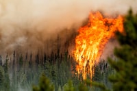 Flames from the Donnie Creek wildfire burn along a ridge top north of Fort St. John, British Columbia, Sunday, July 2, 2023. (AP Photo/Noah Berger)