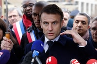France's President Emmanuel Macron, surrounded by officials, attends the inauguration ceremony of the Paris 2024 Olympic village in Saint-Denis, north of Paris, Thursday, Feb. 29, 2024. French President Emmanuel Macron boldly promised to swim in the River Seine being cleaned up for the Paris Olympics as he toured the new complex that will house athletes on Thursday. (Ludovic Marin, Pool via AP)