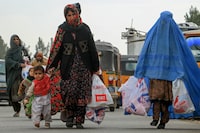 Afghan women carry aid packages which includes food, clothes, and sanitary materials distributed by a local charity foundation in Herat on January 15, 2024. (Photo by Mohsen Karimi / AFP) (Photo by MOHSEN KARIMI/AFP via Getty Images)