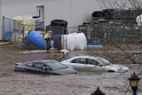 A man walks past cars abandoned in floodwater in a mall parking lot following a major rain event in Halifax on Saturday, July 22, 2023.&nbsp;Nova Scotia RCMP are expected to give an update on the search for a youth who went missing when four people were swept away by rushing floodwater following a historic storm July 22. THE&nbsp;CANADIAN PRESS/Darren Calabrese