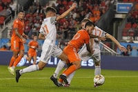 FC Cincinnati's Luciano Acosta burst through the challenges of Toronto FC's Sigurd Rosted and Themi Antonoglou (right) during first half MLS action in Toronto, Saturday, Sept. 30, 2023. THE CANADIAN PRESS/Chris Young