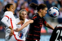 Portland Thorns forward Christine Sinclair keeps her eyes on the ball as she goes up for a header with OL Reign defender Alana Cook, left, during the second half of an NWSL Challenge Cup soccer match Friday, March 18, 2022 in Seattle. (Jennifer Buchanan/The Seattle Times via AP)