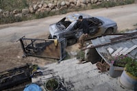 Mohammad Bader, 27, inspects his torched vehicle, in the West Bank village of al-Mughayyir, Saturday, April 13, 2024. Dozens of Israeli settlers stormed into a Palestinian village in the Israeli-occupied West Bank on Friday, shooting and setting houses and cars on fire. The rampage killed a Palestinian man and wounded 25 others, Palestinian health officials said. An Israeli rights group said the settlers were searching for a missing 14-year-old boy from their settlement. (AP Photo/Nasser Nasser)