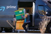 An Amazon Prime delivery person lifts packages while making a stop at an apartment building on Tuesday, Nov. 28, 2023, in Denver. Walmart, Target and Amazon are all-in on the shipping wars, a move retail experts say will help them maintain a competitive edge against low-cost Chinese retailers Shein and Temu. (AP Photo/David Zalubowski)