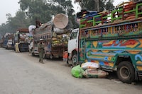A man walks past trucks loaded with belongings as Afghan nationals are returning home, after Pakistan gives the last warning to undocumented immigrants to leave, outside the United Nations High Commissioner for Refugees (UNHCR) repatriation centres in Azakhel town in Nowshera, Pakistan November 1, 2023. REUTERS/Fayaz Aziz
