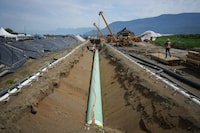 <p>Workers lay pipe during construction of the Trans Mountain pipeline expansion on farmland, in Abbotsford, B.C., on Wednesday, May 3, 2023. After more than four years of construction and at least $34 billion in costs, the Trans Mountain pipeline expansion project is nearly complete. THE CANADIAN PRESS/Darryl Dyck</p>