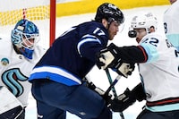 Seattle Kraken's Oliver Bjorkstrand (22) and Winnipeg Jets' Adam Lowry (17) battle for the loose puck during the third period of NHL action in Winnipeg on Tuesday March 5, 2024. THE CANADIAN PRESS/Fred Greenslade