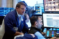 Trader Michael Milano, left, works with colleagues on the floor of the New York Stock Exchange, Friday, Aug. 25.