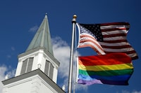 FILE - A gay Pride rainbow flag flies with the U.S. flag in front of the Asbury United Methodist Church in Prairie Village, Kan., on Friday, April 19, 2019. As of June 2023, more than 6,000 United Methodist congregations — a fifth of the U.S. total — have now received permission to leave the denomination amid a schism over theology and the role of LGBTQ people in the nation's second-largest Protestant denomination. (AP Photo/Charlie Riedel, File)