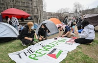 People work on a sign during a pro-Palestinian demonstration at an encampment at McGill University in Montreal, Saturday, April 27, 2024. THE CANADIAN PRESS/Graham Hughes