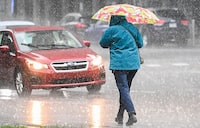 A person walks along a street with an umbrella during heavy rain in Montreal, Saturday, October 7, 2023. Environment Canada has issued a rainfall warning for the province. THE CANADIAN PRESS/Graham Hughes 