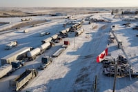 A truck convoy of anti-COVID-19 vaccine mandate demonstrators block the highway at the busy U.S. border crossing at Coutts, Alta., Wednesday, Feb. 2, 2022. Jury selection has started in a trial for three men charged in connection with the blockade. THE CANADIAN PRESS/Jeff McIntosh