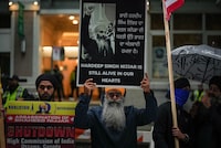 A man holds a sign with a photograph of Hardeep Singh Nijjar during a protest outside the Indian Consulate in Vancouver on Monday, Sept. 25, 2023. The spokesman for a group advocating Sikh independence says that a Metro Vancouver home hit by gunfire on Thursday belonged to a member of the movement. THE CANADIAN PRESS/Darryl Dyck 