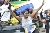 Residents gesture and hold a Gabon national flag as they celebrate in Libreville on August 30, 2023 after a group of Gabonese military officers appeared on television announcing they were "putting an end to the current regime" and scrapping official election results that had handed another term to veteran President Ali Bongo Ondimba. In a pre-dawn address, a group of officers declared "all the institutions of the republic" had been dissolved, the election results cancelled and the borders closed. (Photo by AFP) (Photo by -/AFP via Getty Images)