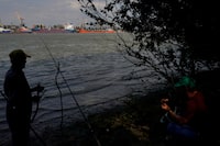 FILE PHOTO: Two men prepare to fish in Plauru, Romania, across the Danube from the Ukrainian port of Izmail, September 5, 2023. REUTERS/Andreea Campeanu/File Photo