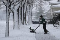 A man cleans the snow off a walkway in front of a house in Wheeling, Ill., Friday, Jan. 12, 2024.  (AP Photo/Nam Y. Huh)