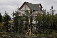 Sprinklers protect a home next to Grace Lake as wildfires threatened the Northwest Territories town of Yellowknife, Canada, August 18, 2023.  REUTERS/Jennifer Gauthier
