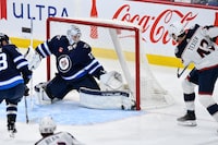 Winnipeg Jets goaltender Connor Hellebuyck (37) makes a save on Columbus Blue Jackets' Alexandre Texier (42) during the third period of NHL action in Winnipeg on Tuesday January 9, 2024. THE CANADIAN PRESS/Fred Greenslade