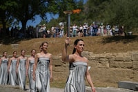 Actress Mary Mina, playing the high priestess , holds a torch with the flame during the final dress rehearsal of the flame lighting ceremony for the Paris Olympics, at the Ancient Olympia site, Greece, Monday, April 15, 2024. The flame for the Paris Olympics will be officially lit Tuesday at the birthplace of the ancient games, and will then be carried through Greece for 11 days before being handed over to Paris organizers on April 26. (AP Photo/Petros Giannakouris)
