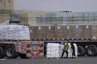 FILE - Trucks carrying humanitarian aid for the Gaza Strip pass through the inspection area at the Kerem Shalom Crossing in southern Israel, Thursday, March 14, 2024. Under heavy U.S. pressure, Israel has promised to ramp up aid to Gaza dramatically, saying last week it would open another cargo crossing and surge more trucks than ever before into the besieged enclave. But days later, there are few signs of those promises materializing and international officials say famine is fast approaching in hard-hit northern Gaza. (AP Photo/Ohad Zwigenberg, File)