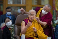 An attendant monk fixes a microphone for Tibetan spiritual leader the Dalai Lama presiding over a function marking his 88th birthday at the Tsuglakhang temple in Dharamshala, India, Thursday, July 6, 2023. (AP Photo/Ashwini Bhatia)