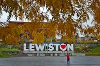 A man photographs a make-shift memorial at the base of the Lewiston sign at Veteran's Memorial Park, Sunday, Oct. 29, 2023, in Lewiston, Maine. The community is working to heal following shooting deaths of 18 people at a bowling alley and a bar in Lewiston on Wednesday, Oct. 25. (AP Photo/Matt York)