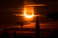 An annular solar eclipse rises over construction cranes and the Peace Tower on Parliament Hill in Ottawa on Thursday, June 10, 2021. THE CANADIAN PRESS/Sean Kilpatrick