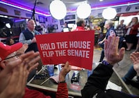 A man holds up a sign as diners applaud Governor Glenn Youngkin who speaks on "Fox & Friends" in a diner on Election Day in Manassas, Virginia, U.S., November 7, 2023. REUTERS/Kevin Lamarque