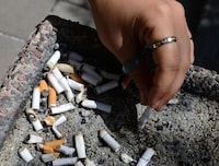 A smoker puts out a cigarette in a public ashtray in Ottawa on May 31, 2016. Three national health organizations want Canada's premiers to push for initiatives to reduce smoking during settlement negotiations with major tobacco companies, which provinces sued to recoup health-care costs. THE CANADIAN PRESS/Sean Kilpatrick