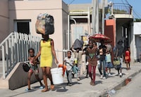 FILE PHOTO: People walk towards a shelter with their belongings fleeing from violence around their homes, in Port-au-Prince, Haiti March 9, 2024. REUTERS/Ralph Tedy Erol/File Photo