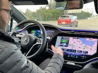Simon Bauer, a development engineer with Mercedes-Benz sits in the driver's seat as the Level 3 driver assist feature takes control in the EQS sedan on a California highway.