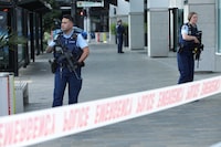 Police officers stand guard near the location of a reported shooting in Auckland, New Zealand on July 20.
