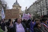 A pro-abortion rights activist holds signs read ' my body, my uterus, my choice' and 'never again' during a rally for abortion rights outside La Sorbonne university in Paris, Wednesday Feb. 28, 2024. France's Senate is voting on a bill meant to enshrine a woman's right to an abortion in the French Constitution. (AP Photo/Michel Euler)