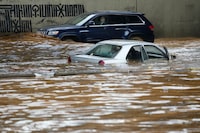 A man, background, drives his car in front a car submerged in flood water at a highway flooded by the rains, in Beirut, Lebanon, Saturday, Dec. 23, 2023. A rainstorm has paralysed parts of Lebanon's cities, turning streets to small rivers, stranding motorists inside their vehicles and damaging homes in some areas. (AP Photo/Hussein Malla)