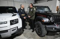 Deputy commissioner Marty Kearns at the Ontario Provincial Police, left, talks with deputy chief Benoit Dube of the Surete du Quebec beside two recovered stolen vehicles during a news conference in Montreal, Wednesday, April 3, 2024. Ontario Provincial Police and the Canada Border Services Agency say they've seized 598 stolen vehicles that were destined for export at the Port of Montreal. THE CANADIAN PRESS/Graham Hughes