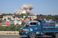 A truck drives on a road as a plume of smoke rises from a building during a reported Russian air strike on Syria's northwestern rebel-held Idlib province, on June 25, 2023. The strikes killed at least 13 people including civilians and children, the deadliest such assault on the war-torn country this year, a war monitor said (Photo by Abdulaziz KETAZ / AFP) (Photo by ABDULAZIZ KETAZ/AFP via Getty Images) *** BESTPIX ***