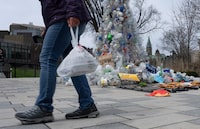 A person carries food in a plastic bag past a plastic public art installation outside the a United Nations conference on plastics on Tuesday, April 23, 2024 in Ottawa.  THE CANADIAN PRESS/Adrian Wyld