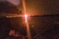 A fireball lights the horizon on the Ukrainian shore of the Danube, seen from Chilia Veche in eastern Romania on the night of Tuesday, Sept. 5, 2023. The discovery of drone debris on Romanian territory this week has left some local residents fearing that the war in neighboring Ukraine could spread into their country, as Russian forces bombard Ukrainian ports just across the Danube River from NATO-member Romania. (Mircea Franc via AP)