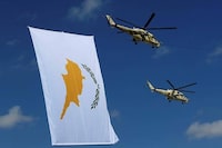 Russian-made military helicopters of the Cypriot air forces fly by a Cyprus' flag during a military parade marking the 57 years celebrations of independence, in Nicosia, in the divided island of Cyprus, Sunday, Oct. 1, 2017. The island of Cyprus has been divided since 1974, when Turkey invaded in response to a coup aimed at uniting the island with Greece. Cyprus gained independence from Britain in 1960.(AP Photo/Petros Karadjias)