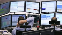 A trader scratches his head as he watches his screens on the trading floor of Frankfurt stock exchange