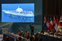 A screen shows a Chinese aircraft carrier at the opening of the Western Pacific Navy Symposium in Qingdao, eastern China's Shandong province on Monday, April 22, 2024. Zhang Youxia, one of China's top military leaders took a harsh line on regional territorial disputes, telling an international naval gathering in northeastern China on Monday that the country would strike back with force if its interests came under threat. (AP Photo/Ng Han Guan)