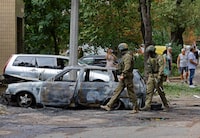 Russian service members walk near a burnt car following recent shelling in the course of Russia-Ukraine conflict in Donetsk, Russian-controlled Ukraine, September 1, 2023. REUTERS/Alexander Ermochenko