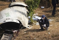 A French investigator takes a photo of the wreckage of a passenger plane at the crash site, in Pokhara, Nepal, Wednesday, Jan.18, 2023. Nepalese authorities are returning to families the bodies of plane crash victims and are sending the aircraft's data recorder to France for analysis as they try to determine what caused the country's deadliest air accident in 30 years. The flight plummeted into a gorge on Sunday while on approach to the newly opened Pokhara International Airport in the foothills of the Himalayas, killing all 72 aboard.(AP Photo/Yunish Gurung)