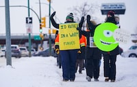 People hold signs while walking at a demonstration site during a provincewide, one-day strike organized by the members of Saskatchewan Teachers’ Federation in Saskatoon, Sask., on Monday, January 22, 2024. THE CANADIAN PRESS/Heywood Yu