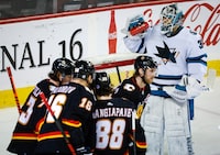 San Jose Sharks goalie Kaapo Kahkonen, right, takes a drink as Calgary Flames players celebrate a goal during first period NHL hockey action in Calgary, Alta., Saturday, March 25, 2023.THE CANADIAN PRESS/Jeff McIntosh