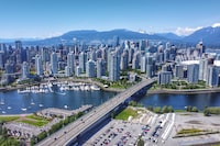 A sunny mid 2020 aerial shot of downtown Vancouver, Yaletown, a marina, North Shore mountains, BC Place, False Creek and the Cambie bridge.