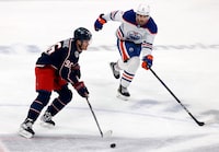 Columbus Blue Jackets forward Jack Roslovic, left, controls the puck in front of Edmonton Oilers defenseman Evan Bouchard during the third period of an NHL hockey game in Columbus, Ohio, Saturday, Feb. 25, 2023. The Blue Jackets won 6-5. (AP Photo/Paul Vernon)