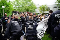 Police officers try to remove a banner held by pro-Palestinian activists at the university campus of the Free University of Berlin, Germany, on May 7, 2024 as police forces try to break up a demonstration of activists against Israel's war in the Gaza Strip which was sparked by Hamas's unprecedented October 7 attack. According to local media reports, activists set up a protest camp with tents in a courtyard of the university. The university has ordered the evacuation and called the police, who have cordoned off the area. (Photo by Tobias SCHWARZ / AFP) (Photo by TOBIAS SCHWARZ/AFP via Getty Images)