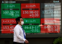 A man walks past an electric monitor displaying the Japanese yen exchange rate against the U.S. dollar, Euro and other foreign currencies outside a brokerage in Tokyo, Japan May 2, 2023.  REUTERS/Issei Kato/File photo